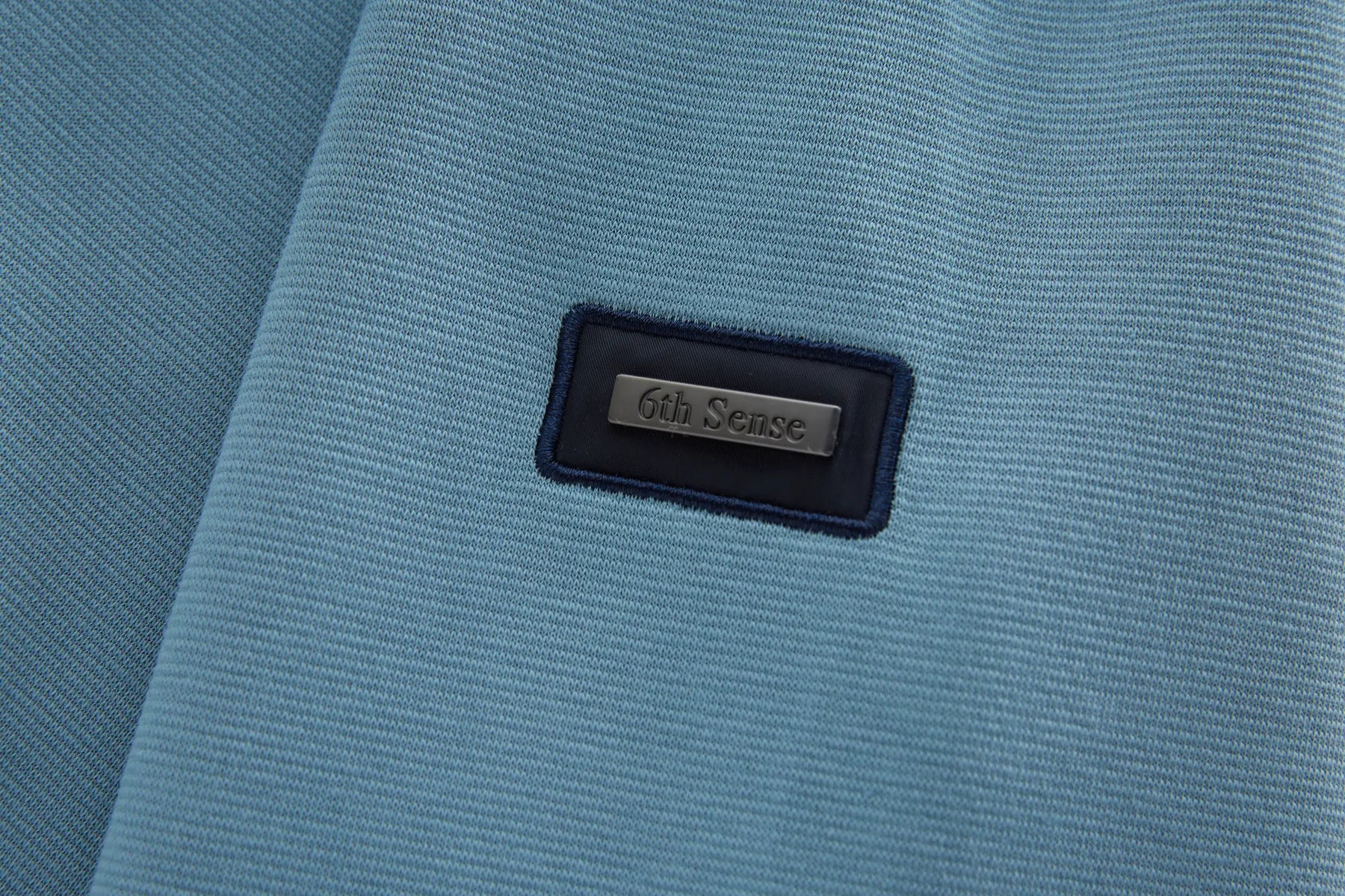 Close-up of a blue fabric surface with a '6th Sense' label.