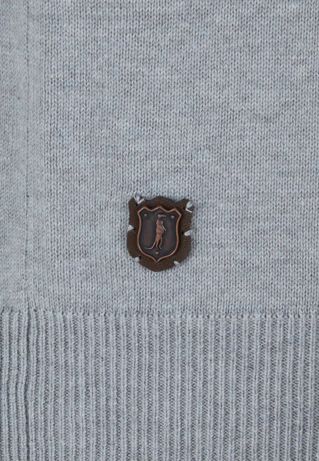 Close-up of a gray sweater with a logo on a light gray background