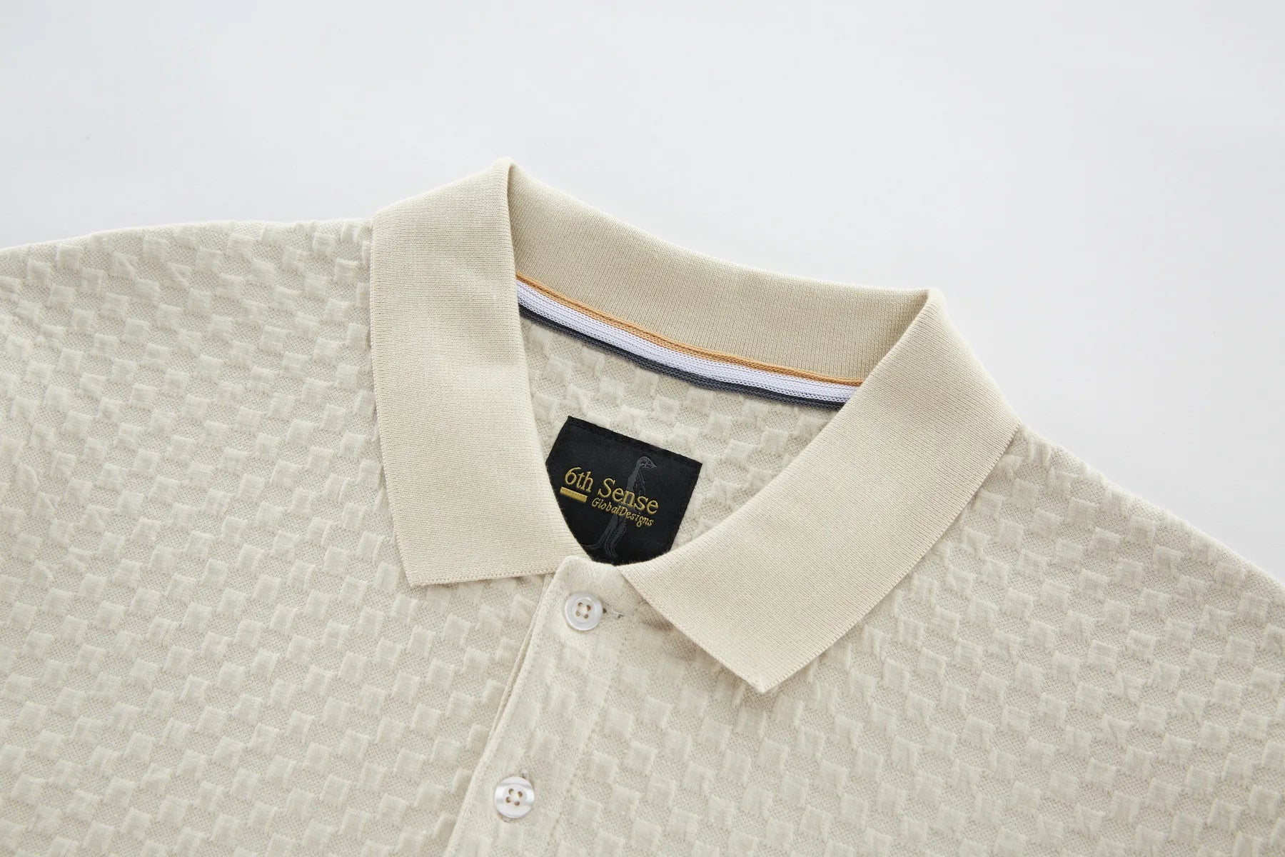 Close-up of a beige shirt collar with a brand label on a light gray background