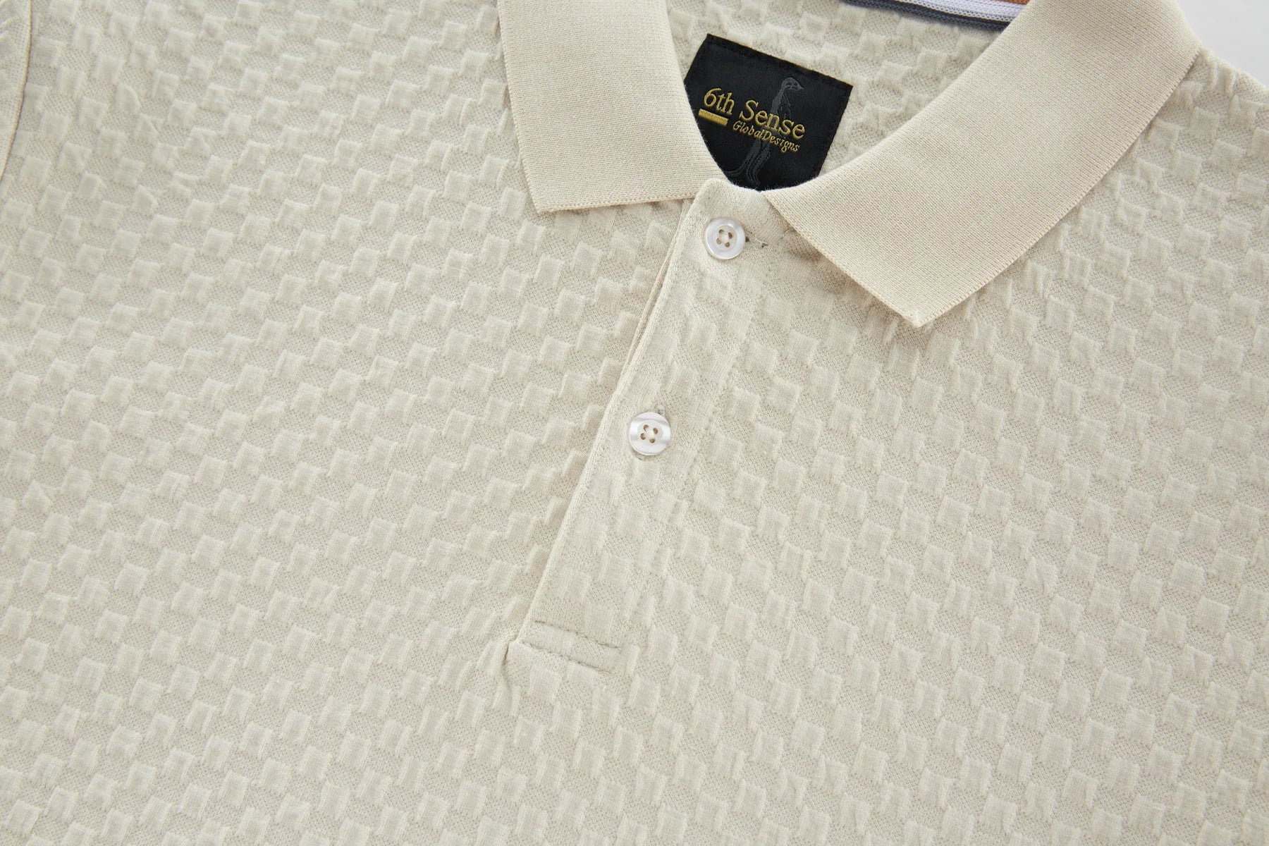 Close-up of a beige textured polo shirt with a collar, featuring a brand label.