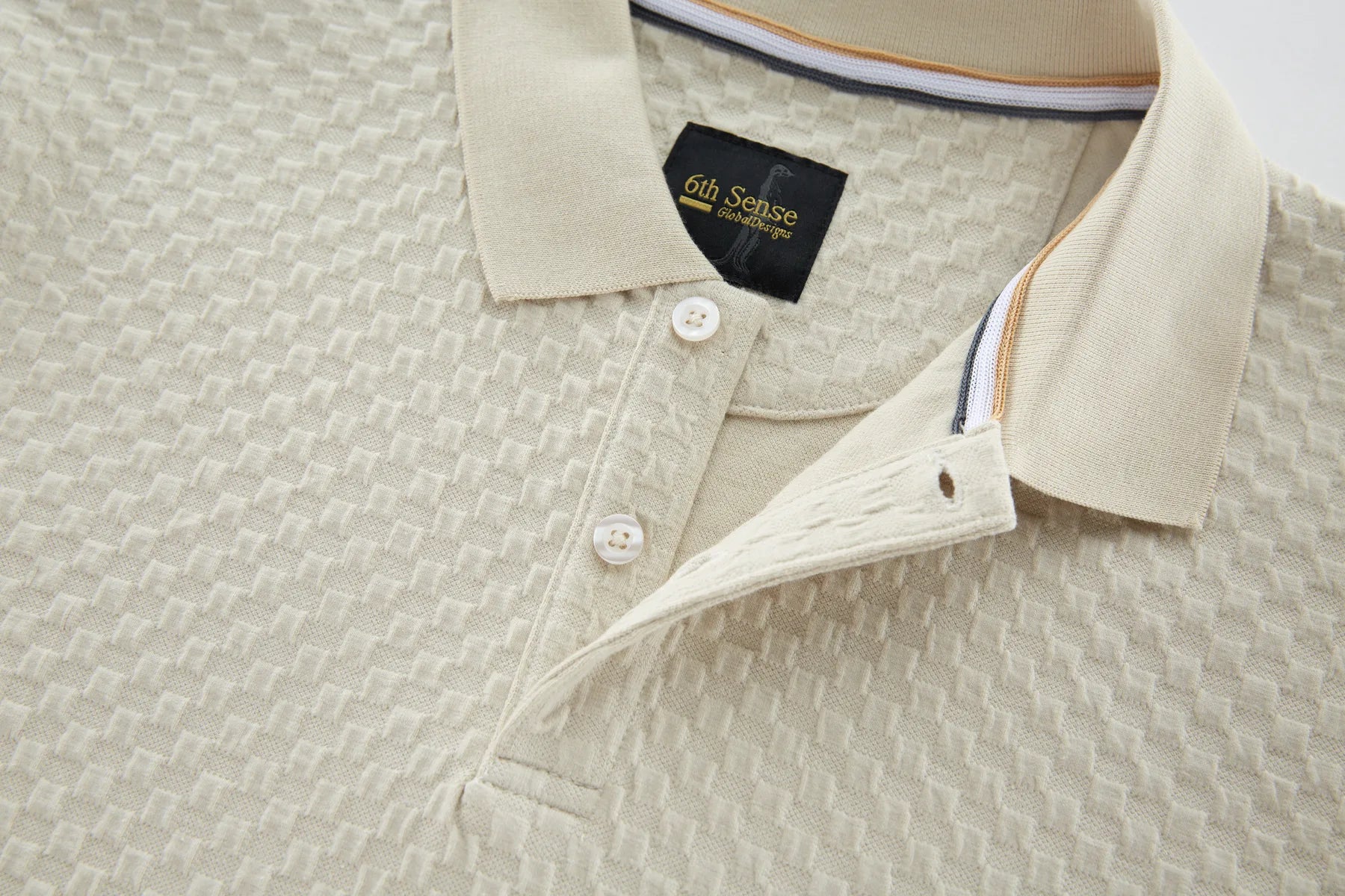 Close-up of a beige textured shirt with a brand label on the collar.