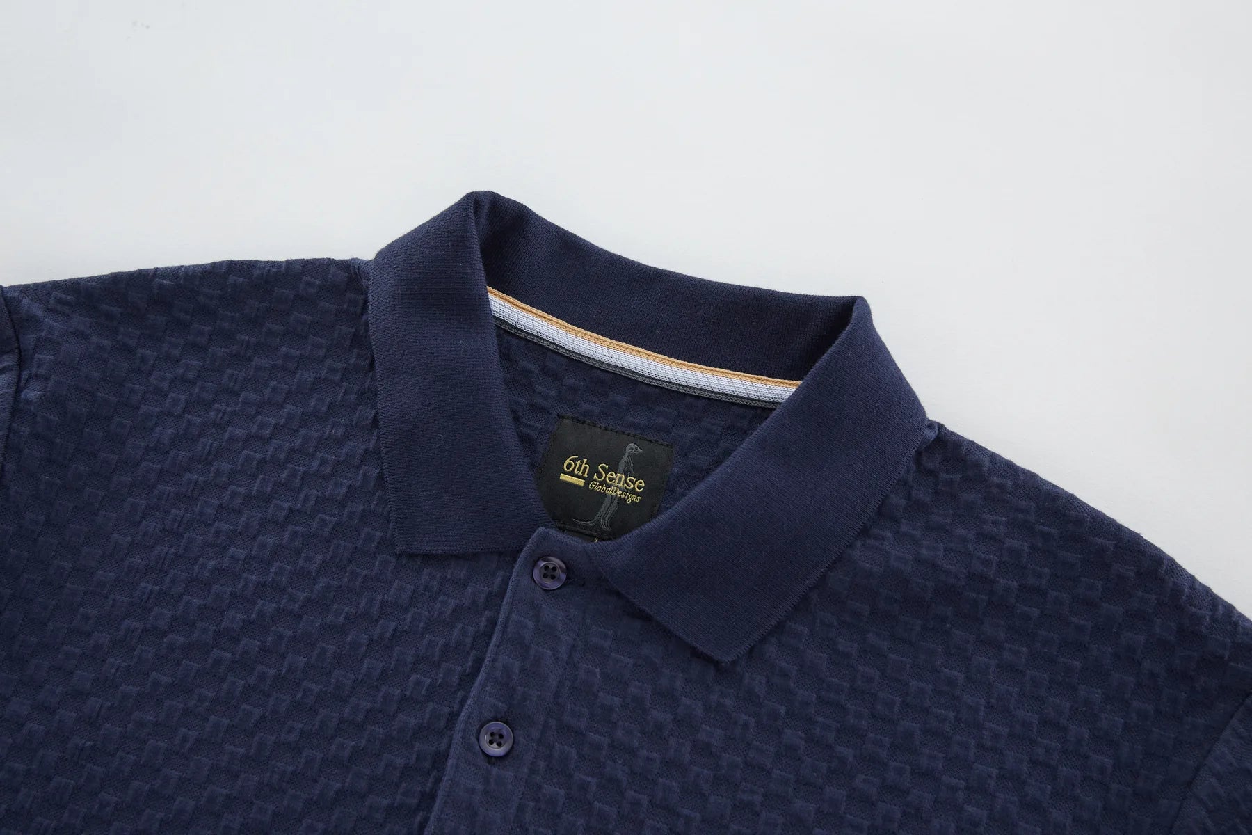 Navy blue polo shirt with a brand label on a light gray background collar close up view
