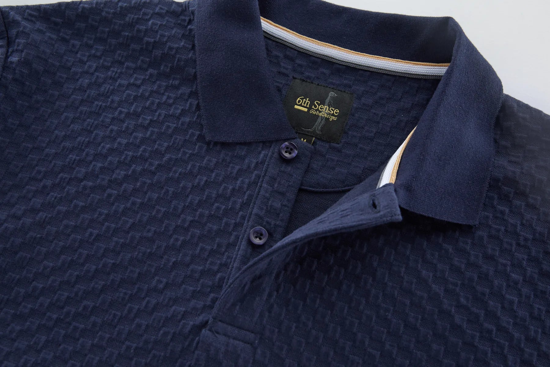 Navy blue textured polo shirt with a brand label on a light gray background open collar view