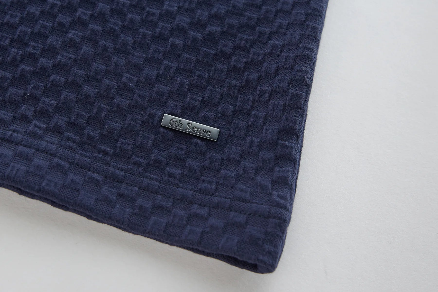 Navy blue textured fabric with a brand label on a light gray background