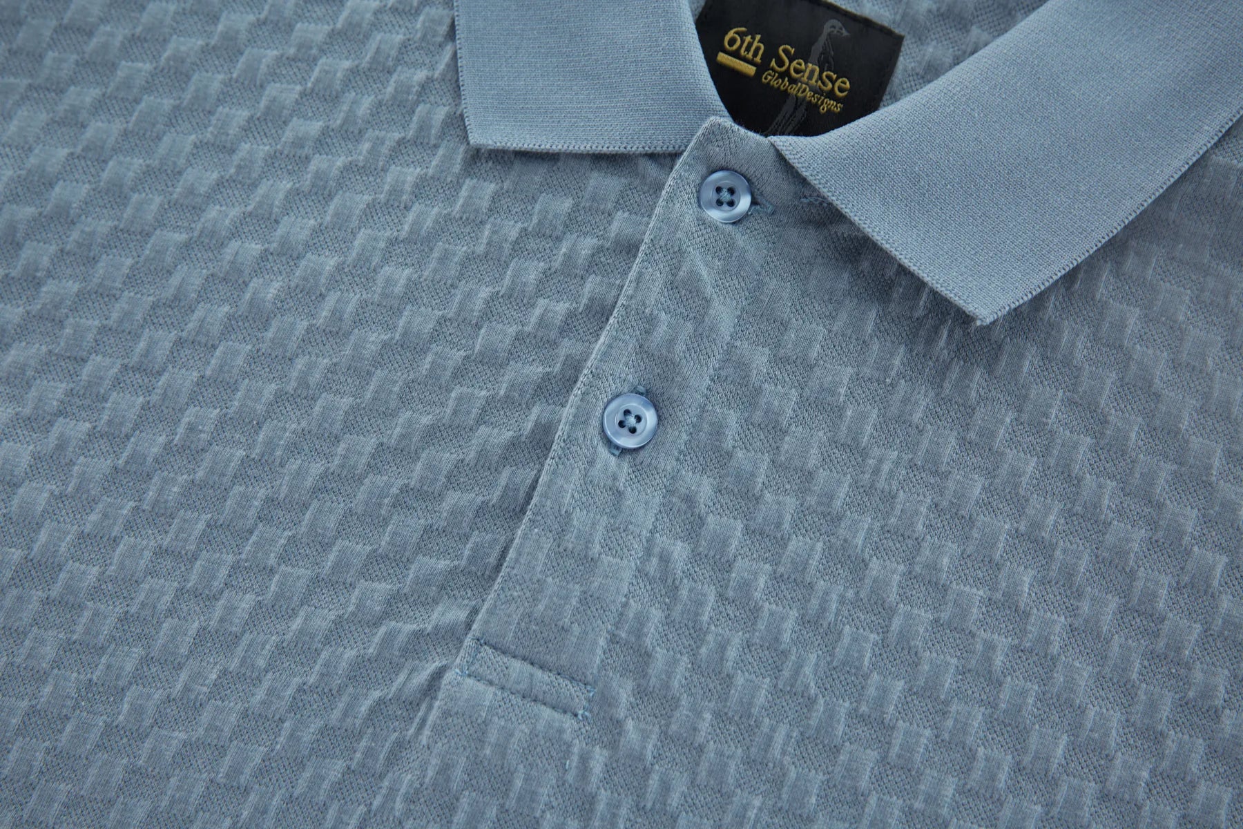 Close-up of a gray textured polo shirt with '6th Sense' branding.