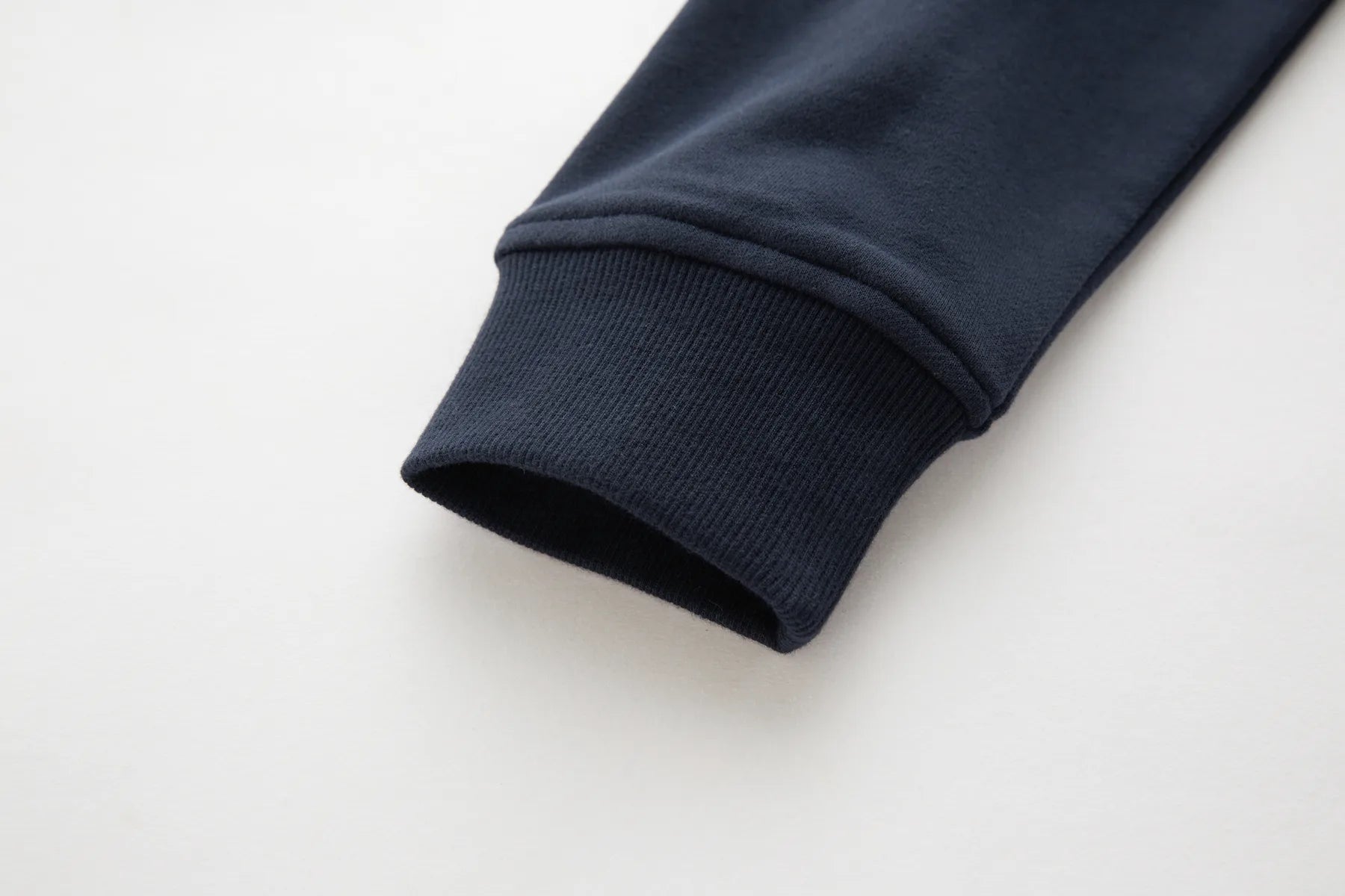 Close-up of a Sammy full zip sapphire navy jacket sleeve on a light gray background