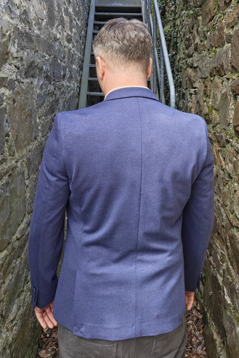 Man in a blue blazer walking up a stone staircase between two stone walls.
