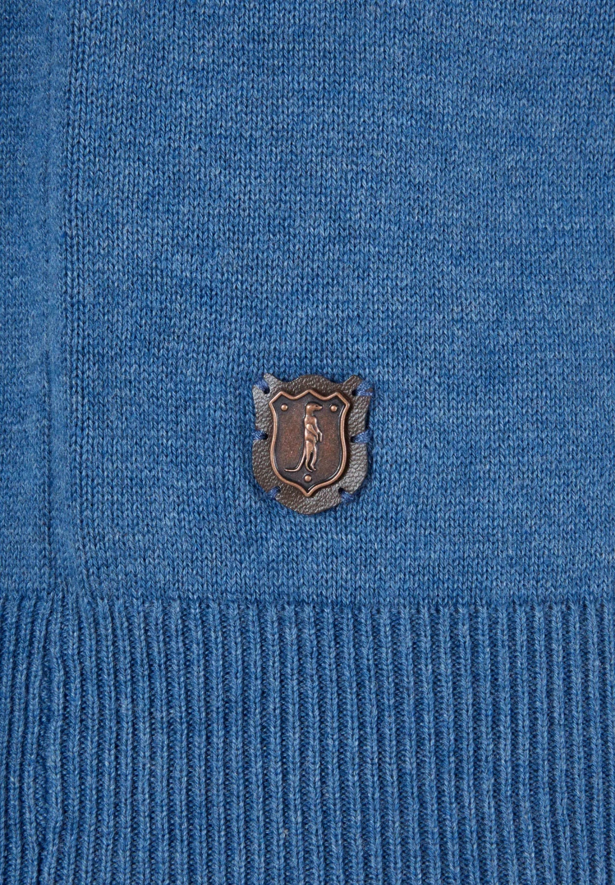 Close-up of a blue sweater with a logo on the chest.