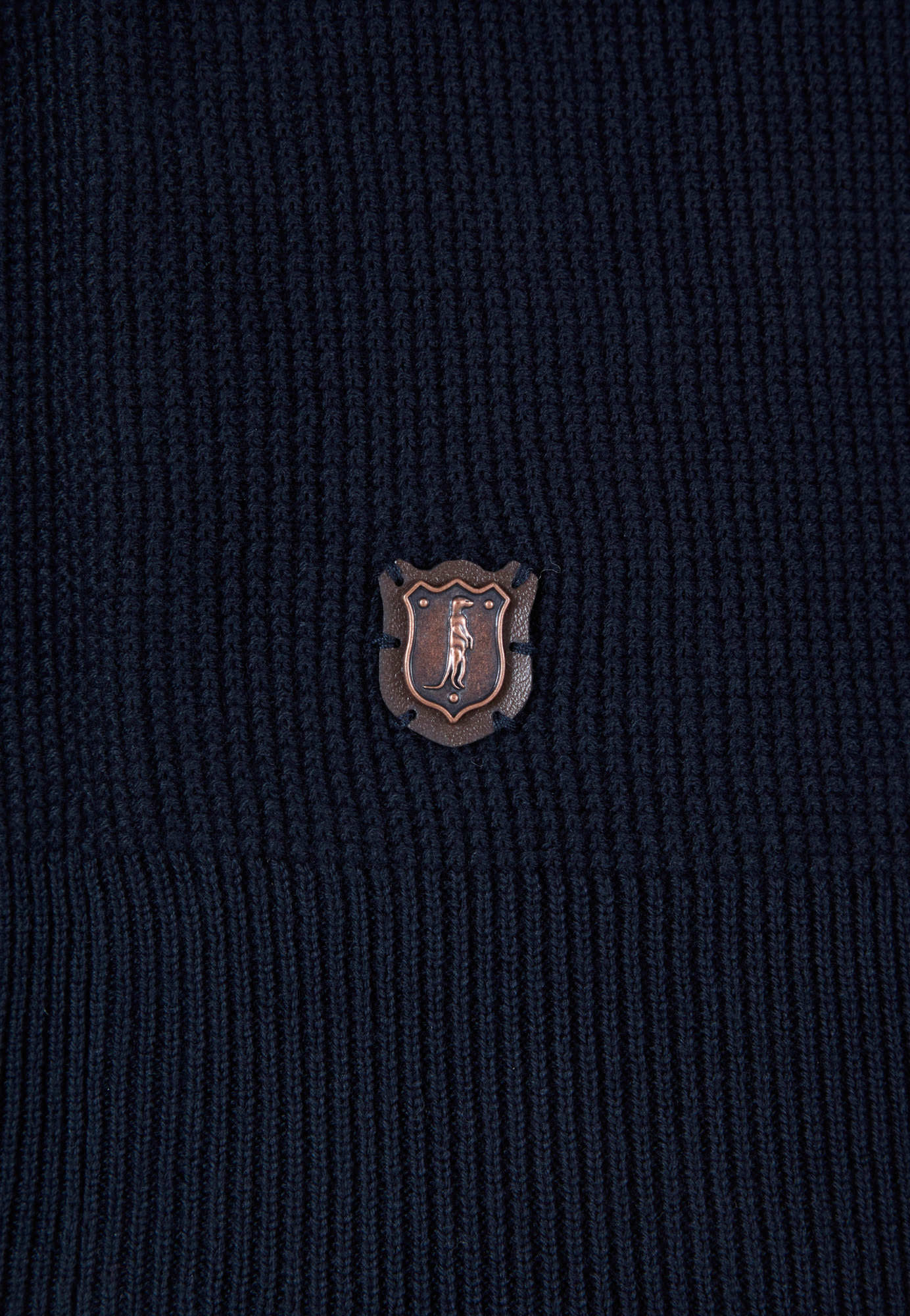 Close-up of a dark textured fabric with a small logo in the center.