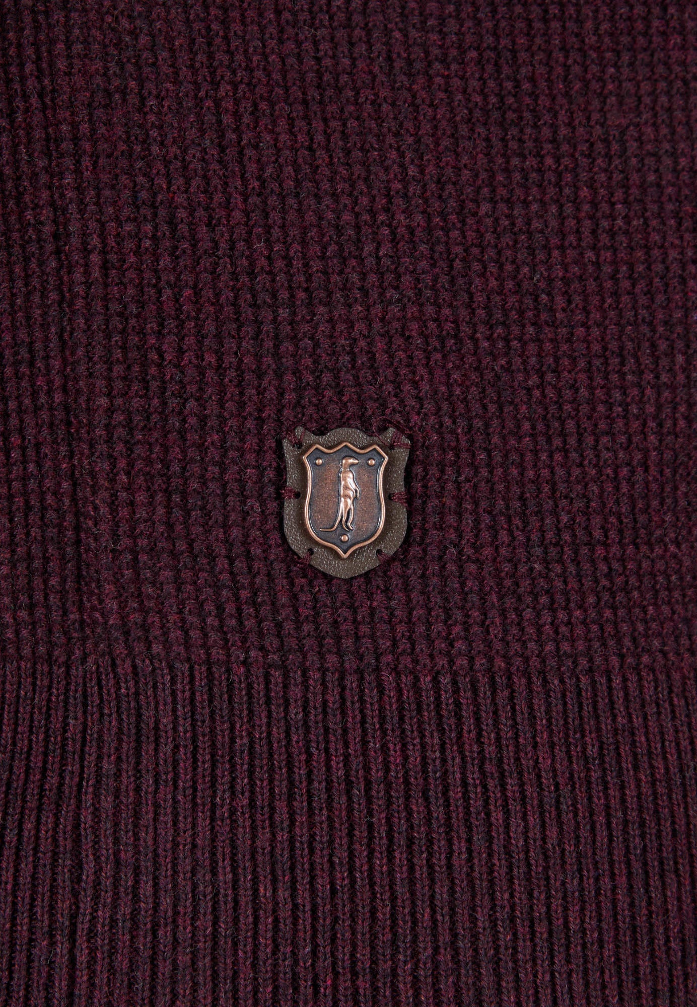 Close-up of a maroon fabric with a small emblem in the center.