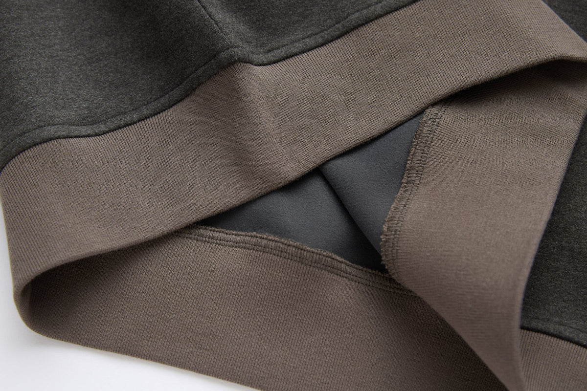 Close-up of the 6th Sense peat sweat's hem and side seam, showing contrast ribbing and stitching.