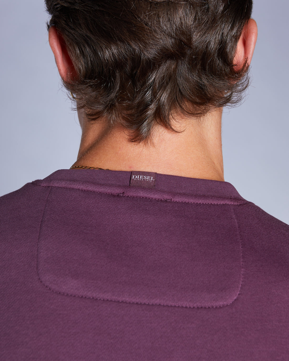 Purple shirt with a visible brand logo on a plain background