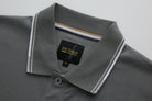Close-up of the 6th Sense Astound December Polo in December, showing the collar, button placket, and inner neck label. The collar has white and brown striped trim, and the black woven label features the 6th Sense Global Designs logo with a size M tag below.
