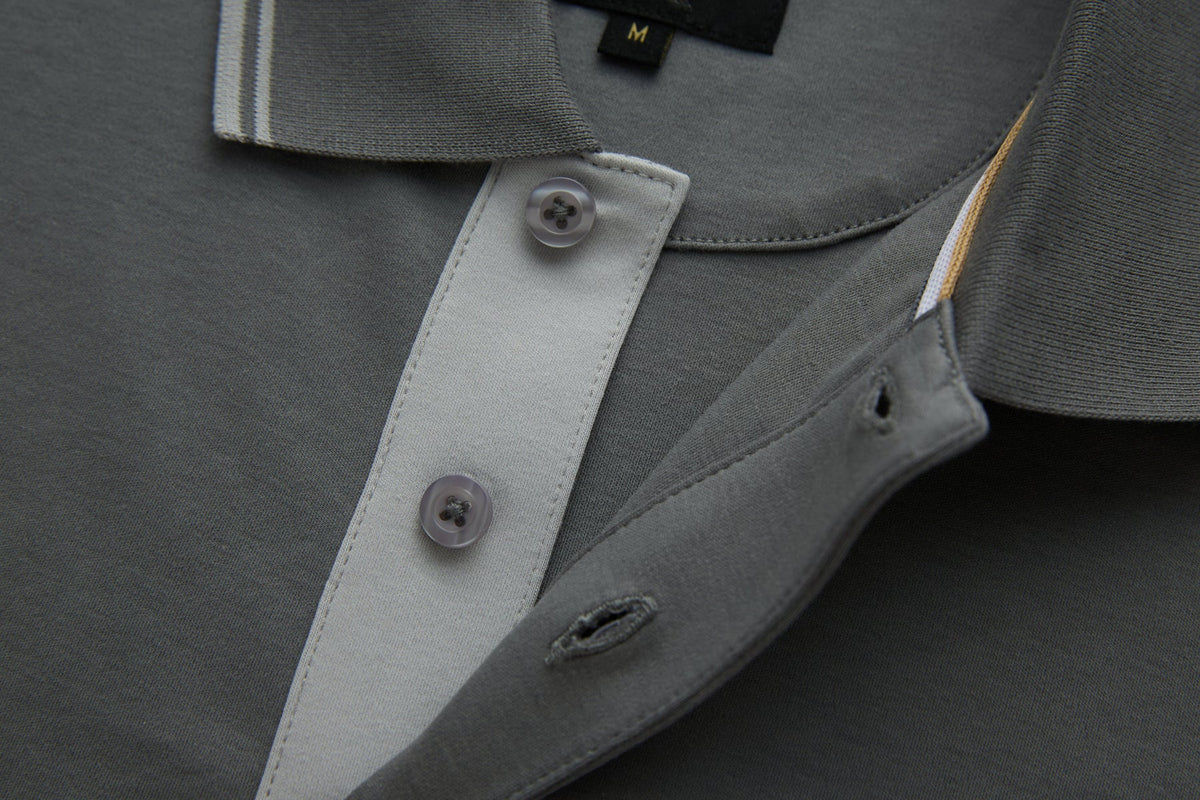 Close-up of the 6th Sense Astound December Polo showing the December grey collar, a button placket with two buttons, buttonholes, and a size M label.