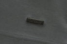 Close-up of the 6th Sense Astound December Polo in December showing a black rectangular rubberised 6th Sense logo badge on textured fabric above a double stitched seam.
