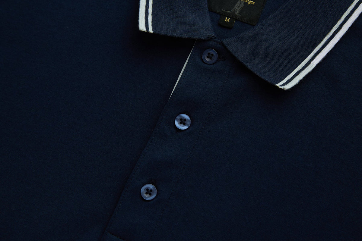 Close-up of the 6th Sense Astound Eclipse Polo in Eclipse, showing the placket, three buttons, ribbed collar with white tipping, and a branded size M label.