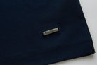 Close-up of the lower hem on the 6th Sense Astound Eclipse Polo in Eclipse, showing dark fabric with double stitching and a small rectangular metal tag engraved with the 6th Sense logo.