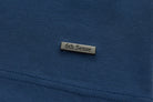 Rectangular 6th Sense metal logo badge on the lower front of the blue Astound Ensign Polo.