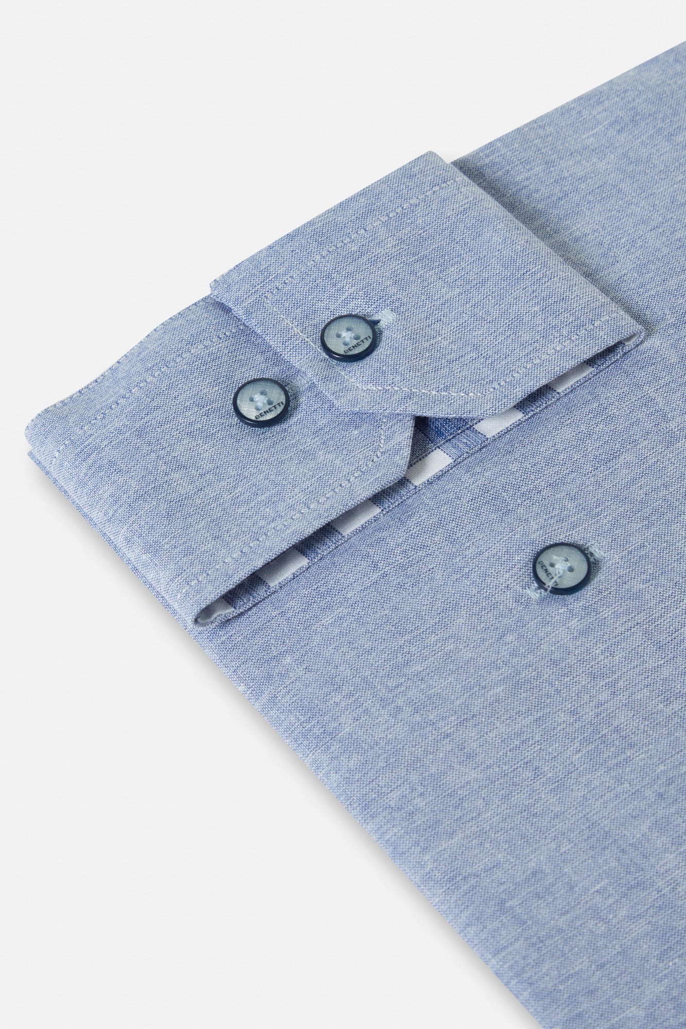 Close-up of a light blue shirt collar with buttons on a white background