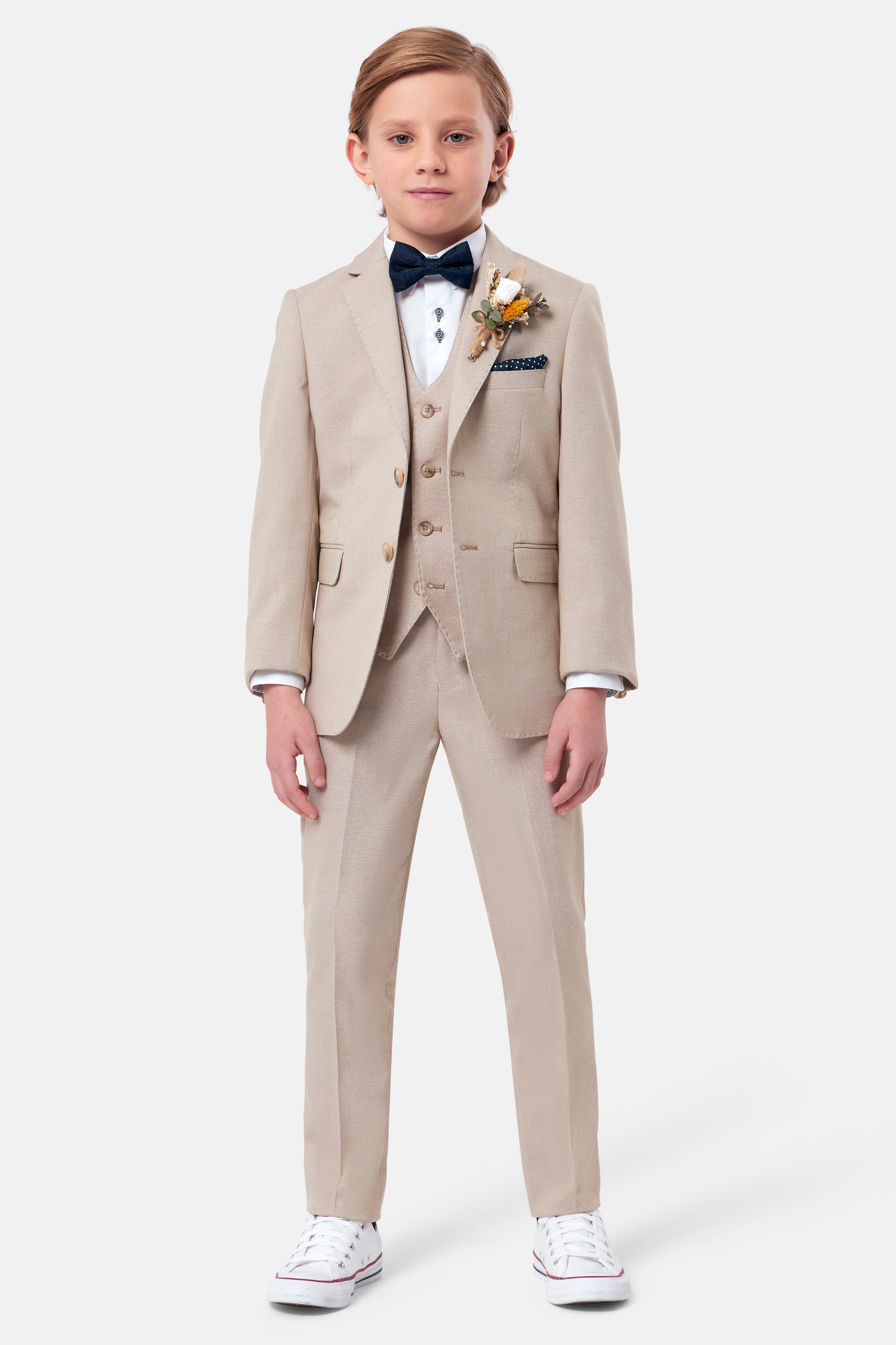 Young boy in a beige suit with a white shirt and black bow tie on a white background