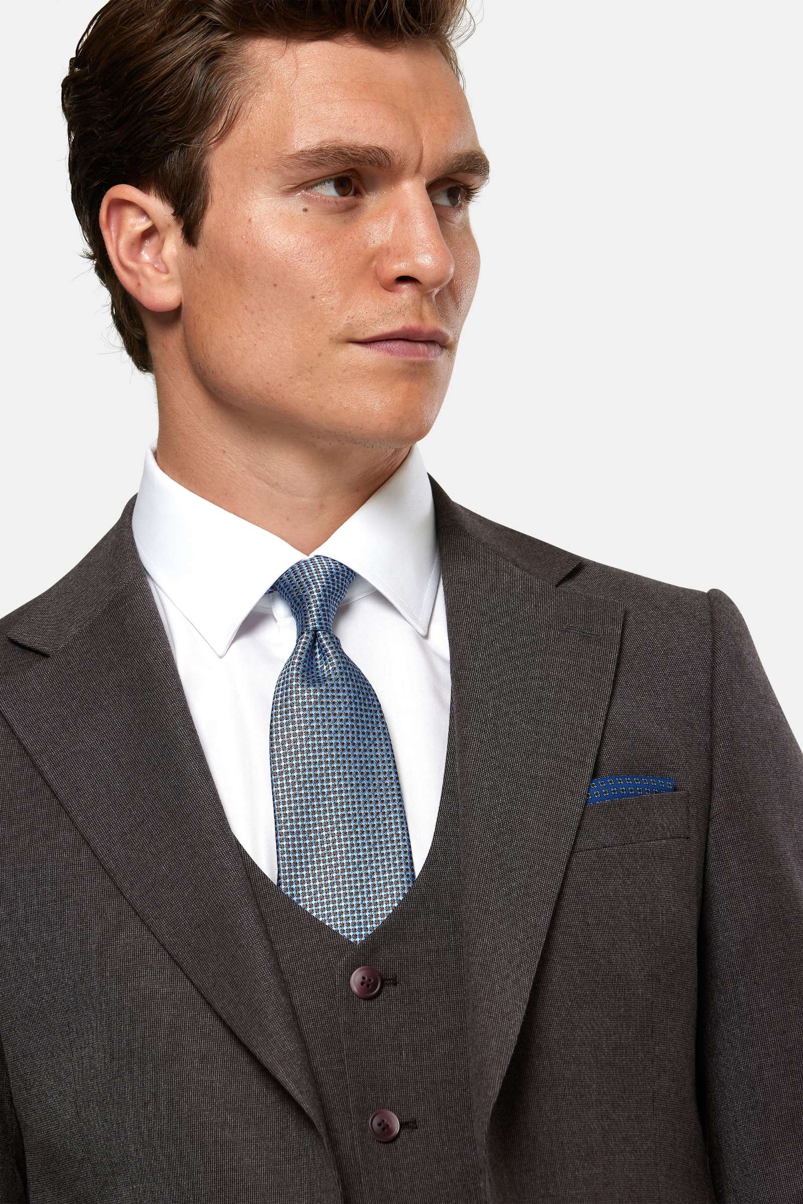 Man wearing a burgundy suit with a blue tie against a white background