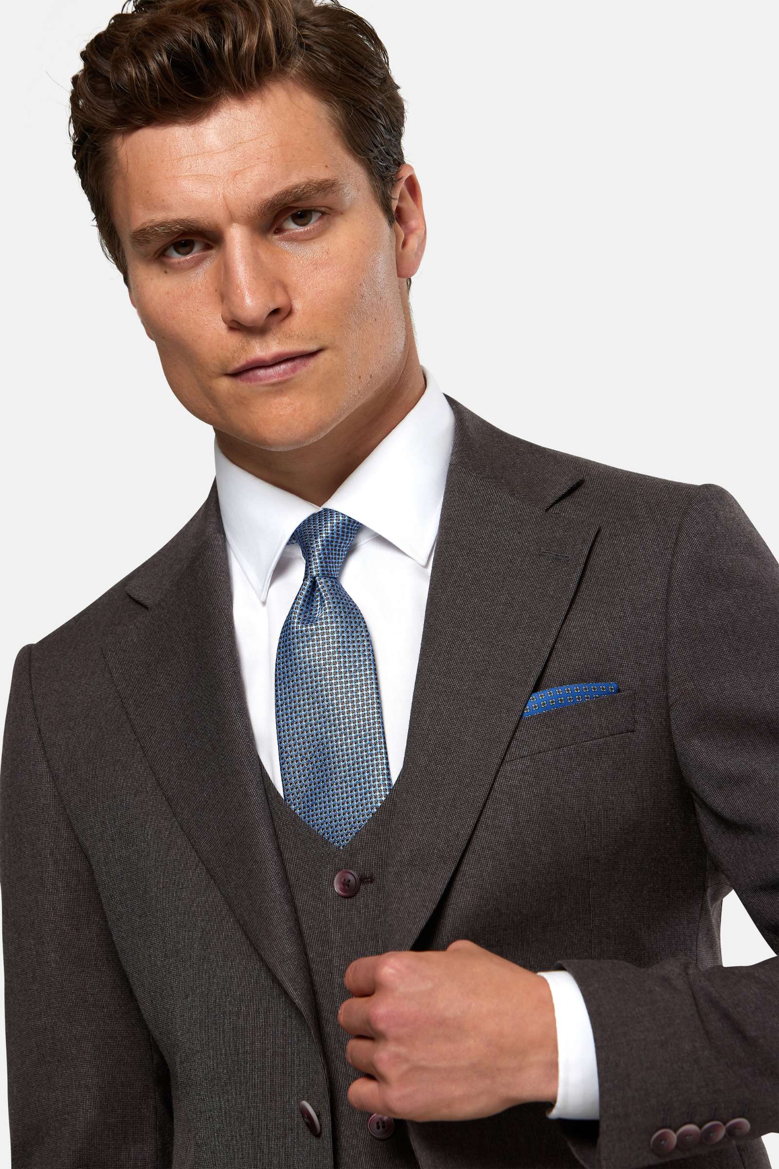 Man wearing a burgundy suit with a blue tie against a light gray background