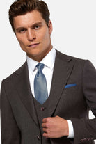 Man wearing a burgundy suit with a blue tie against a light gray background