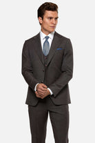 Man wearing a burgundy suit with a blue tie and pocket square on a white background