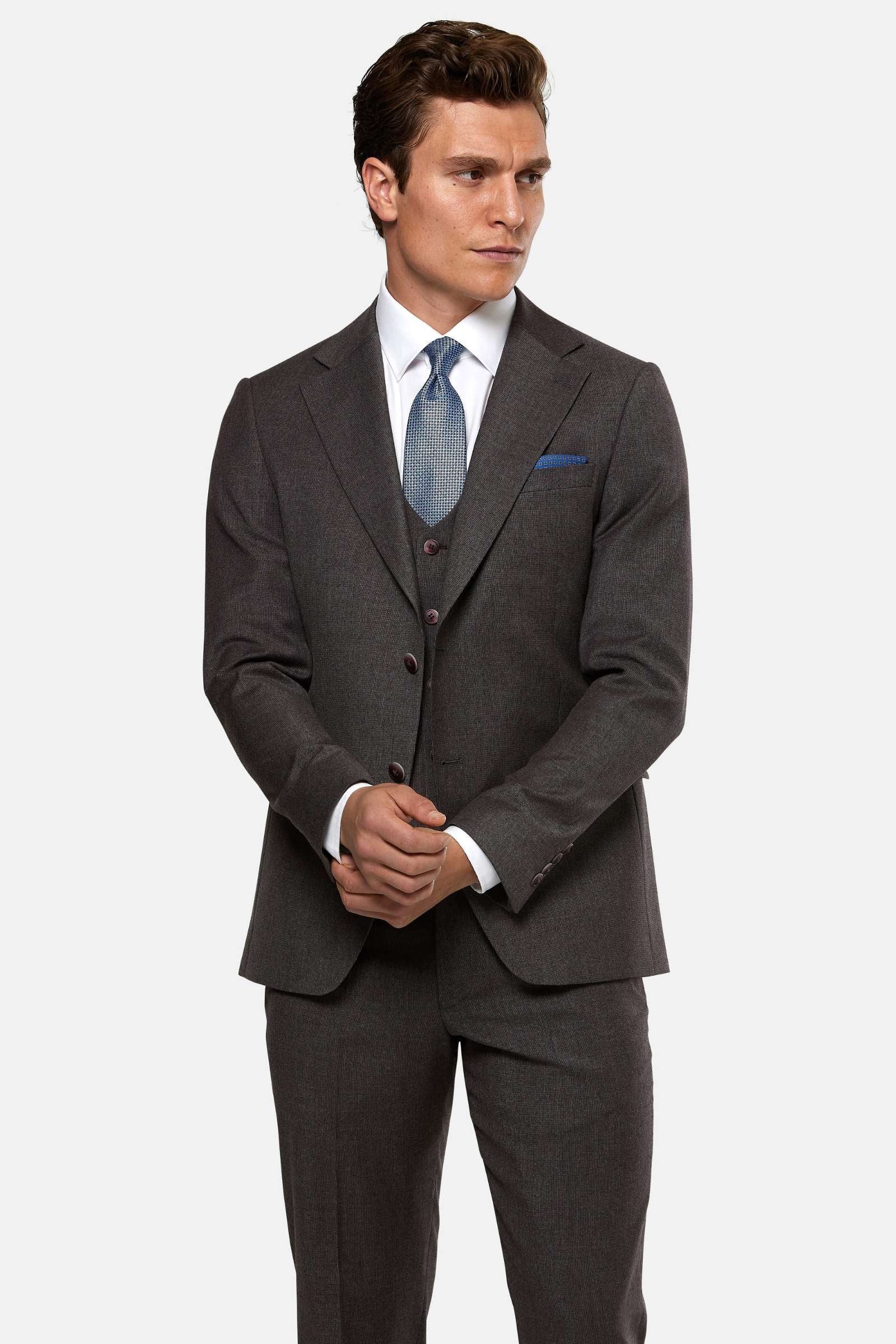 Man wearing a burgundy suit with a blue tie and pocket square on a white background