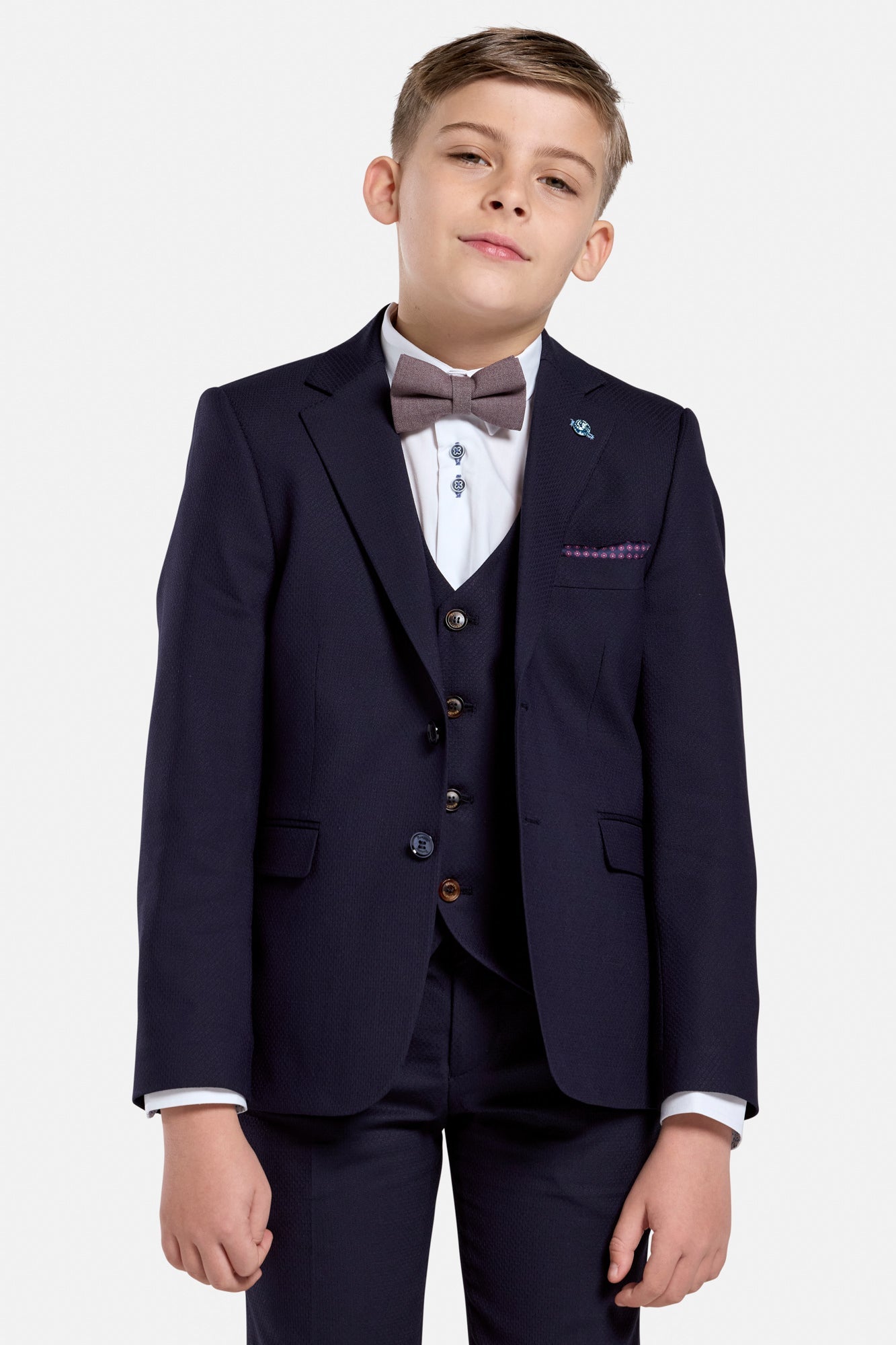 Young boy wearing a formal navy suit jacket with a bow tie on a white background