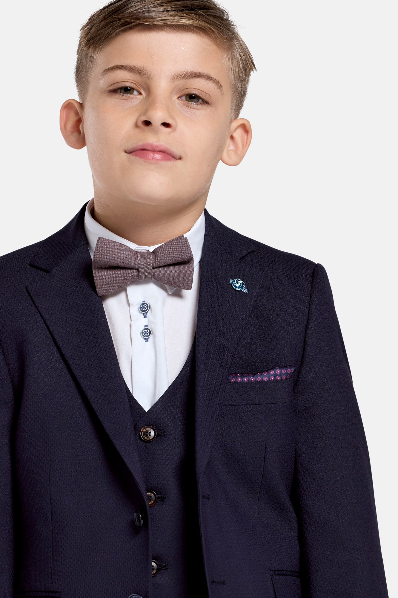 Young boy wearing a formal navy suit  jacketwith a bow tie on a white background