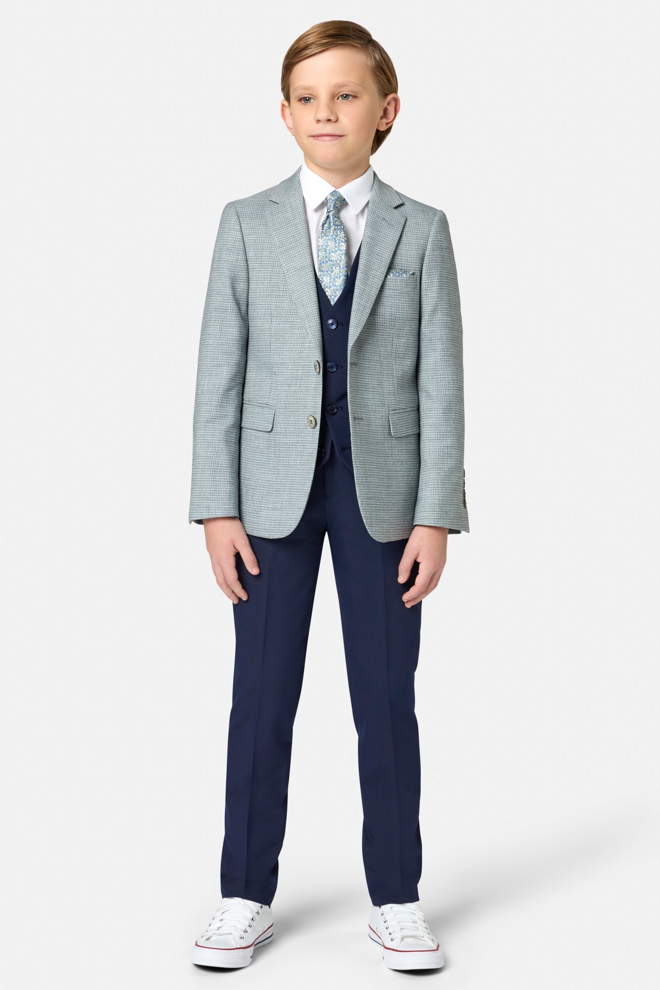 Young boy wearing a sage green checkered blazer with a white shirt and blue tie on a white background