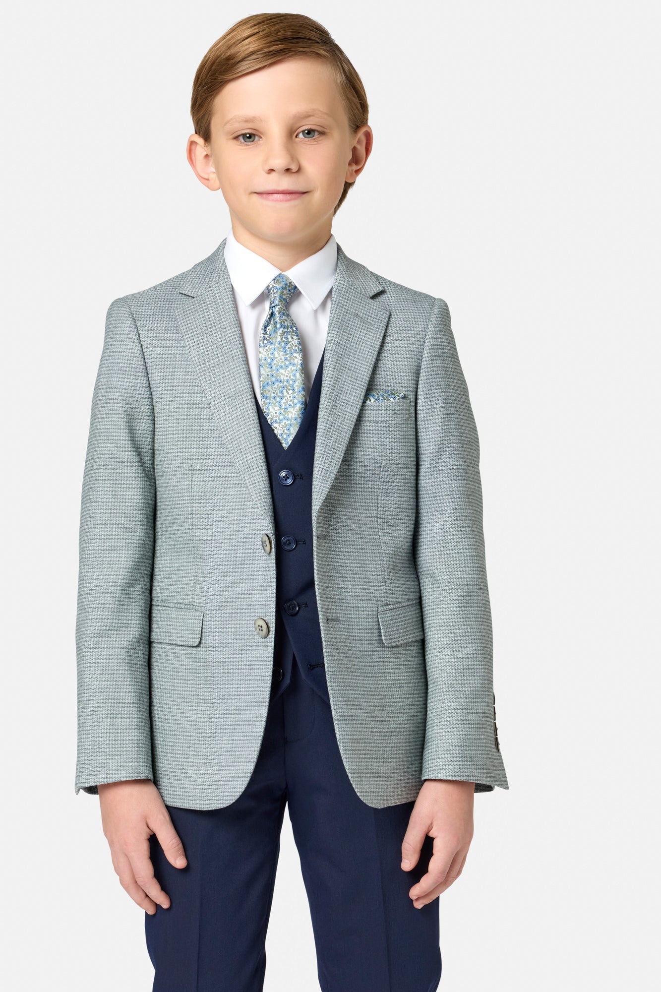 Young boy wearing a formal suit with a sage green blazer and navy pants on a white background