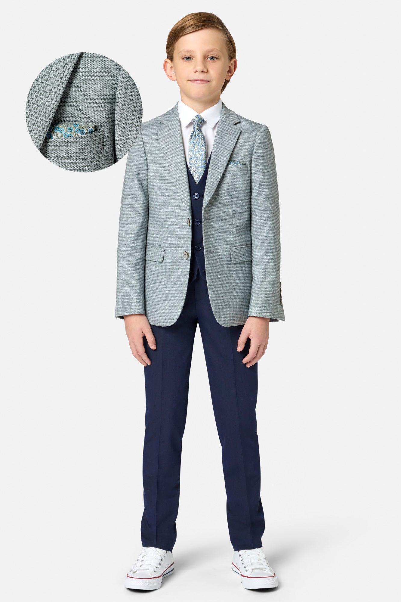 Young boy wearing a sage green checkered blazer with a white shirt and red shoes on a white background.