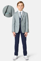 Young boy wearing a sage green checkered blazer with a white shirt and red shoes on a white background.