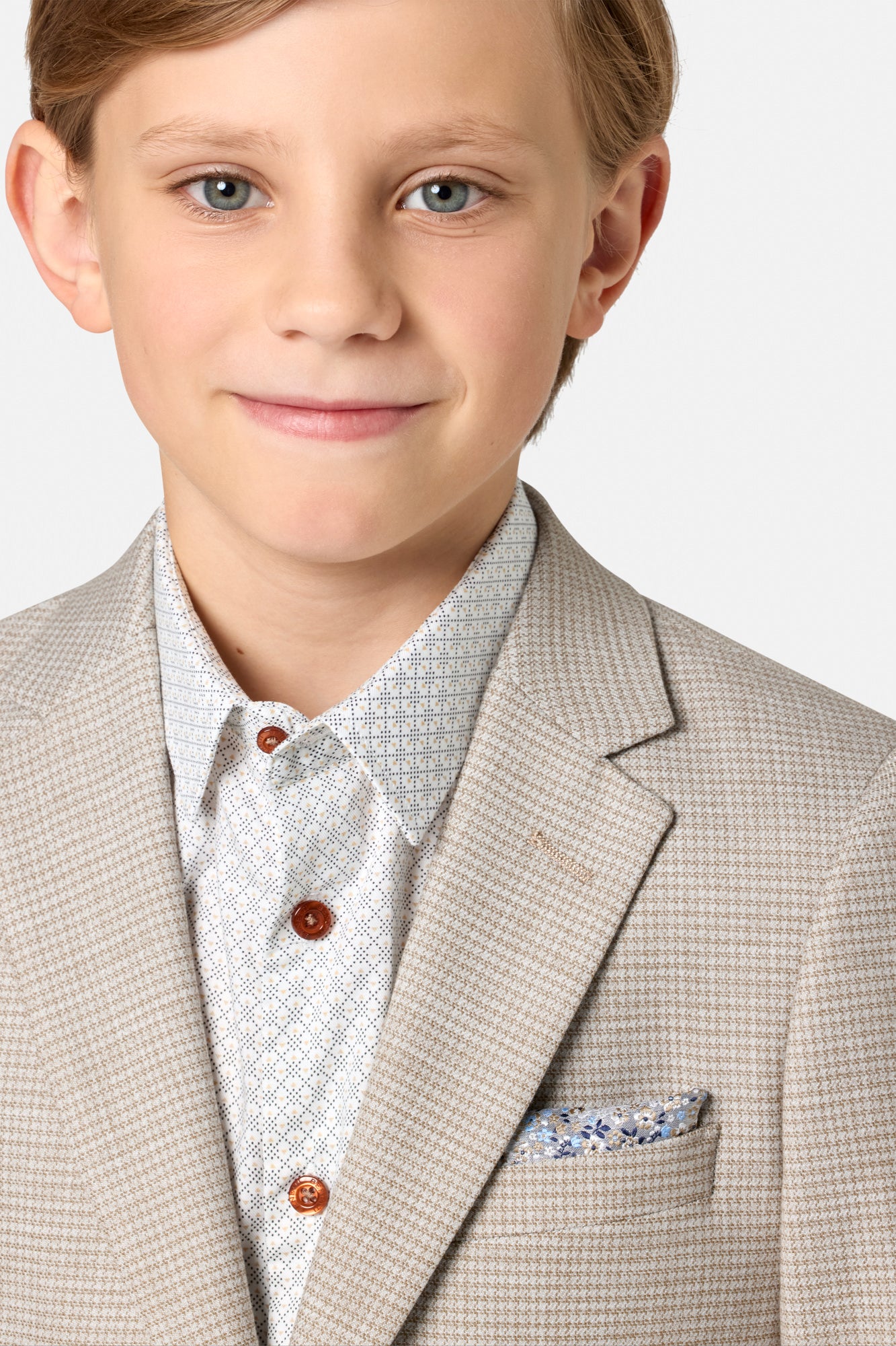Young boy wearing a beige checkered suit with a white shirt and patterned pocket square.