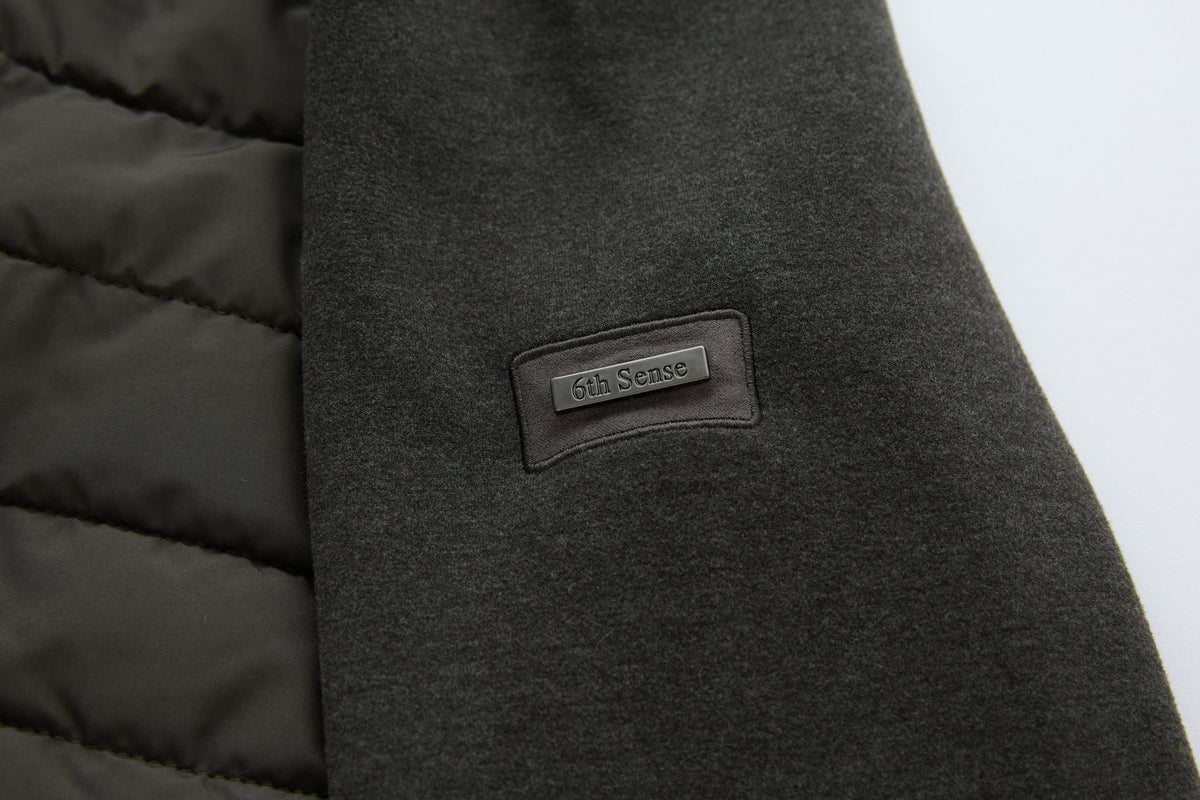 6th Sense Cloud Hybrid Full Zip Peat Jacket detail showing the brand's name on a metal plaque stitched to the sleeve.