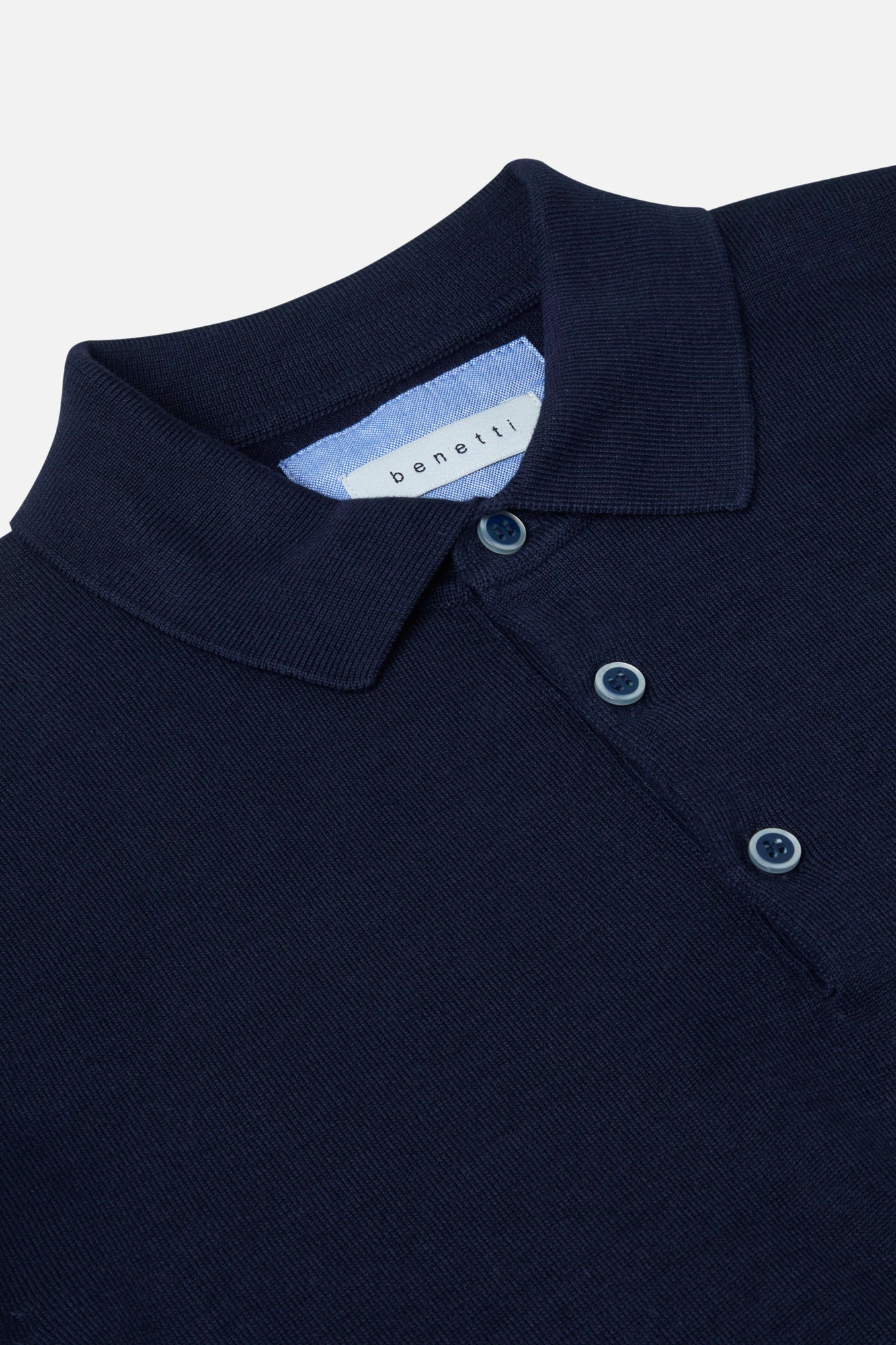 Navy blue polo shirt with a brand label on a light gray background