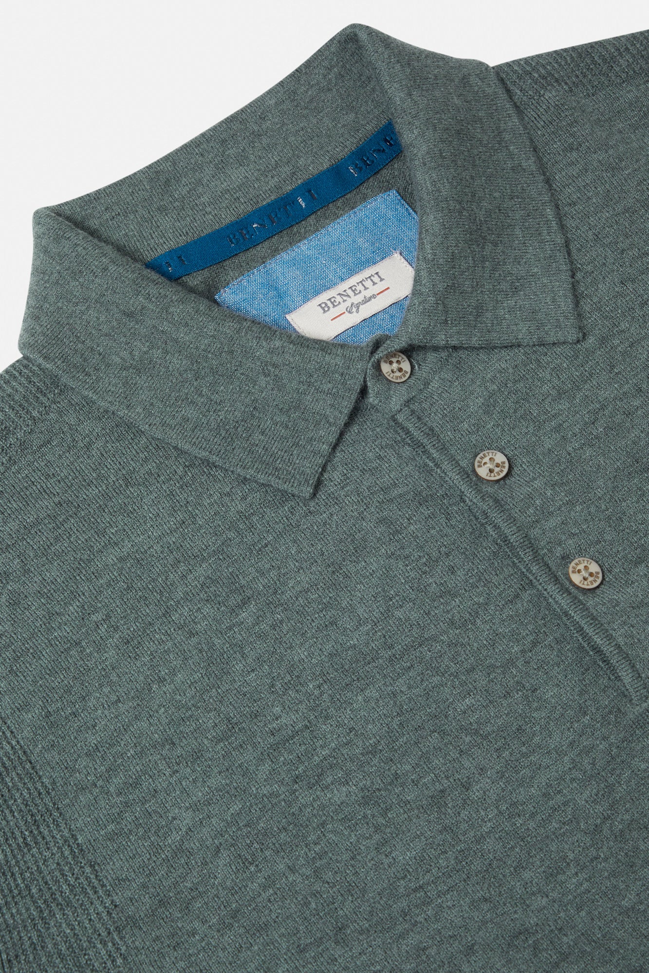 Green polo shirt with a close-up of the collar and buttons on a light gray background