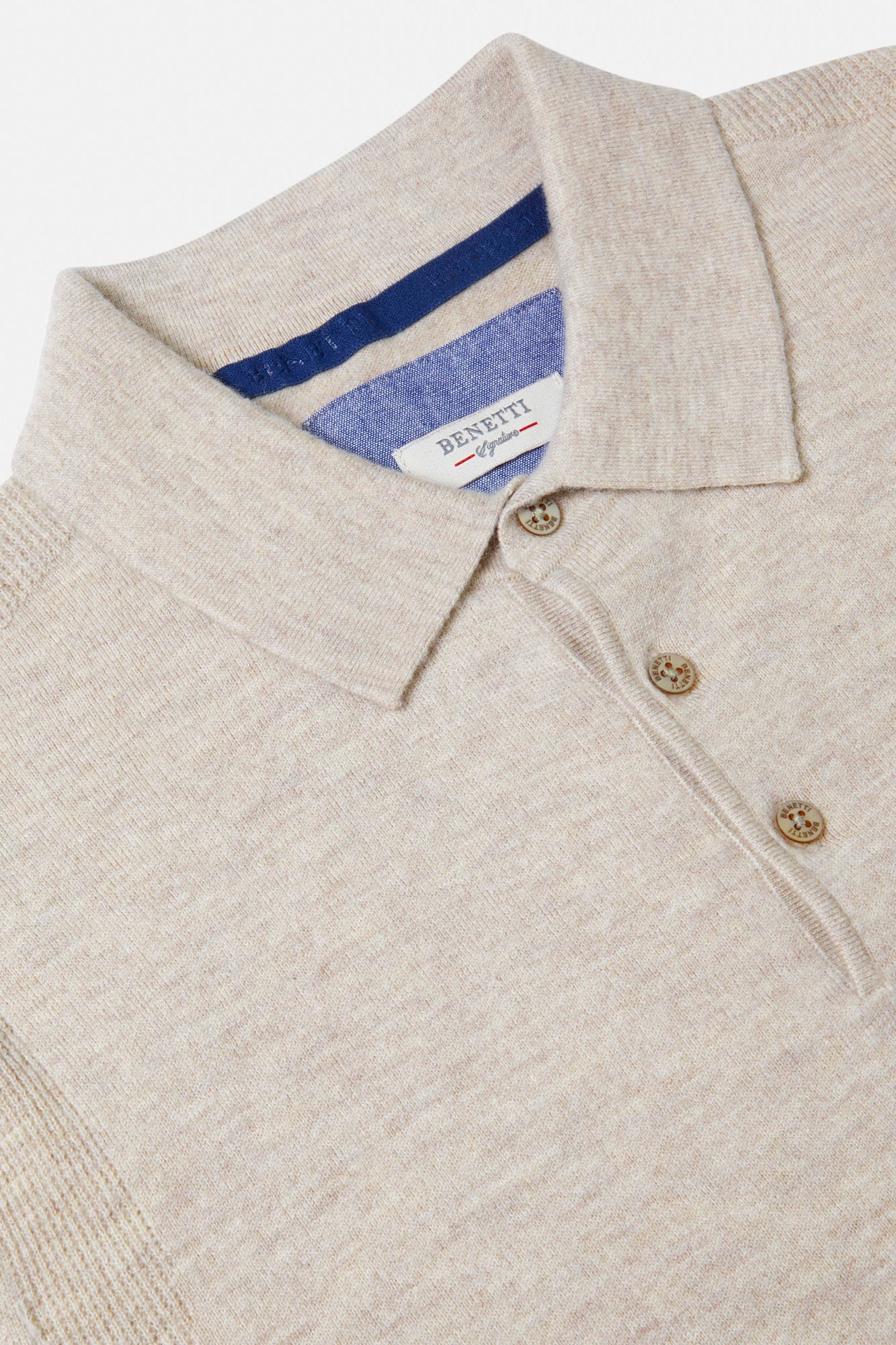 Close-up of a beige sweater with a brand label on a white background