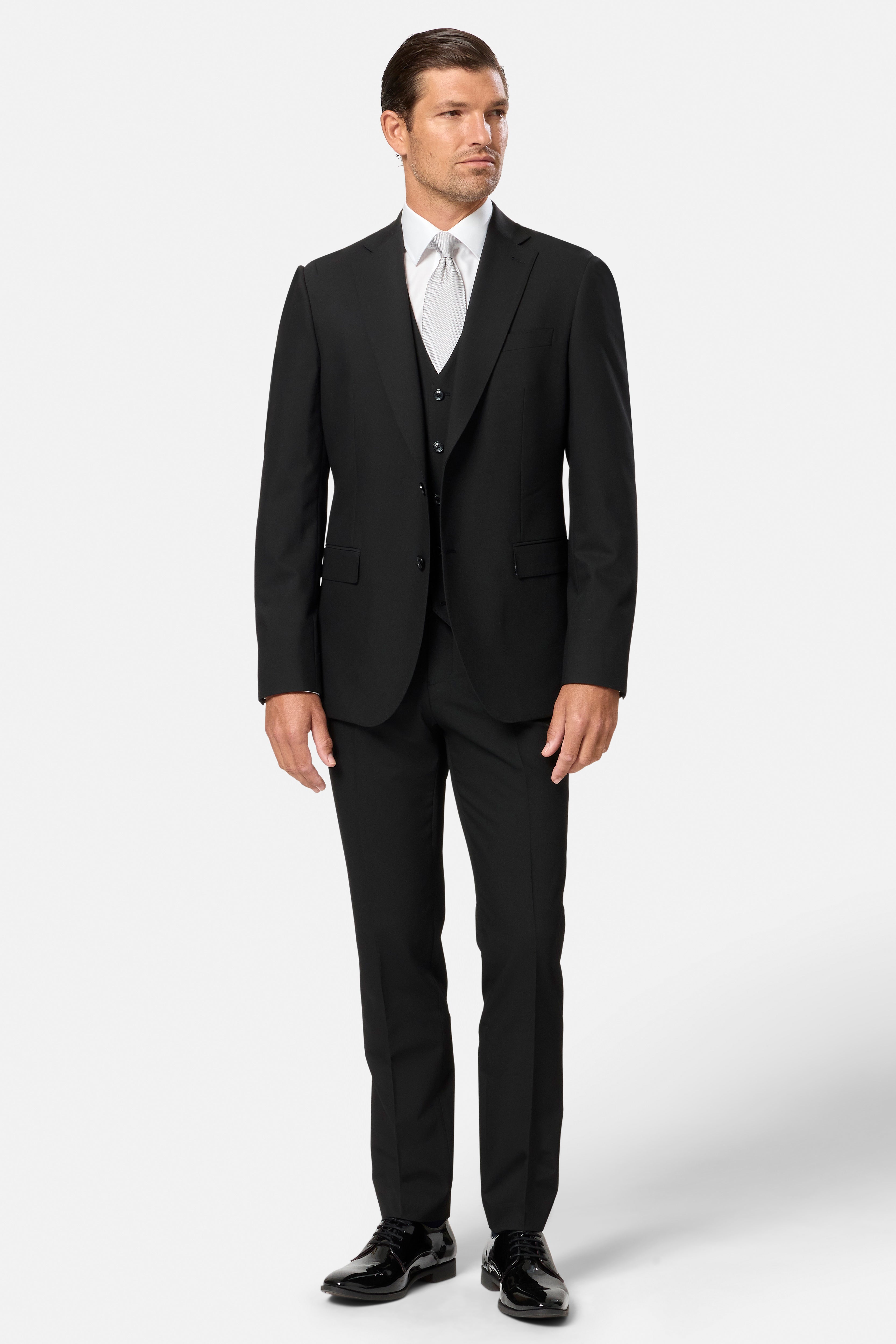 Man wearing a black suit with black waistcoat with a white shirt on a white background