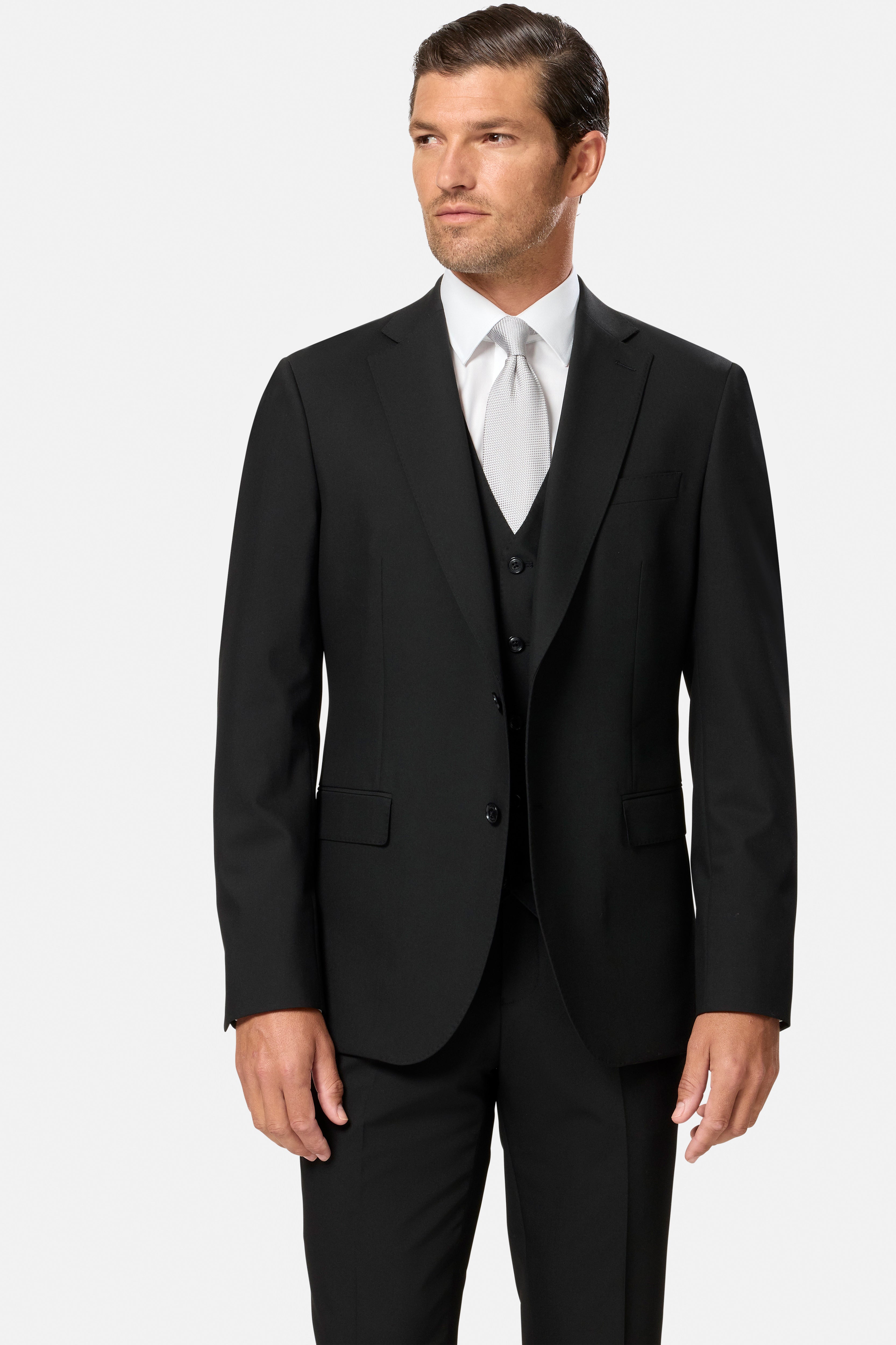 Man wearing a black suit with a white shirt on a light gray background