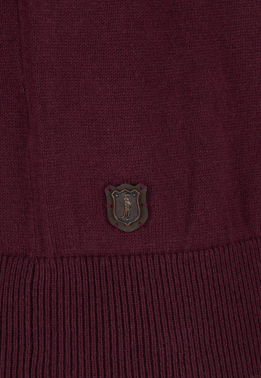 Close-up of a maroon sweater with a logo on the chest.