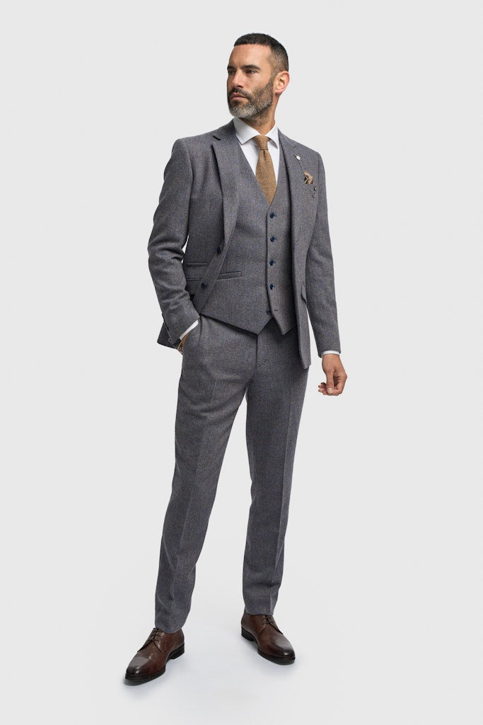 Man wearing a gray suit with a white shirt and brown tie on a light gray background