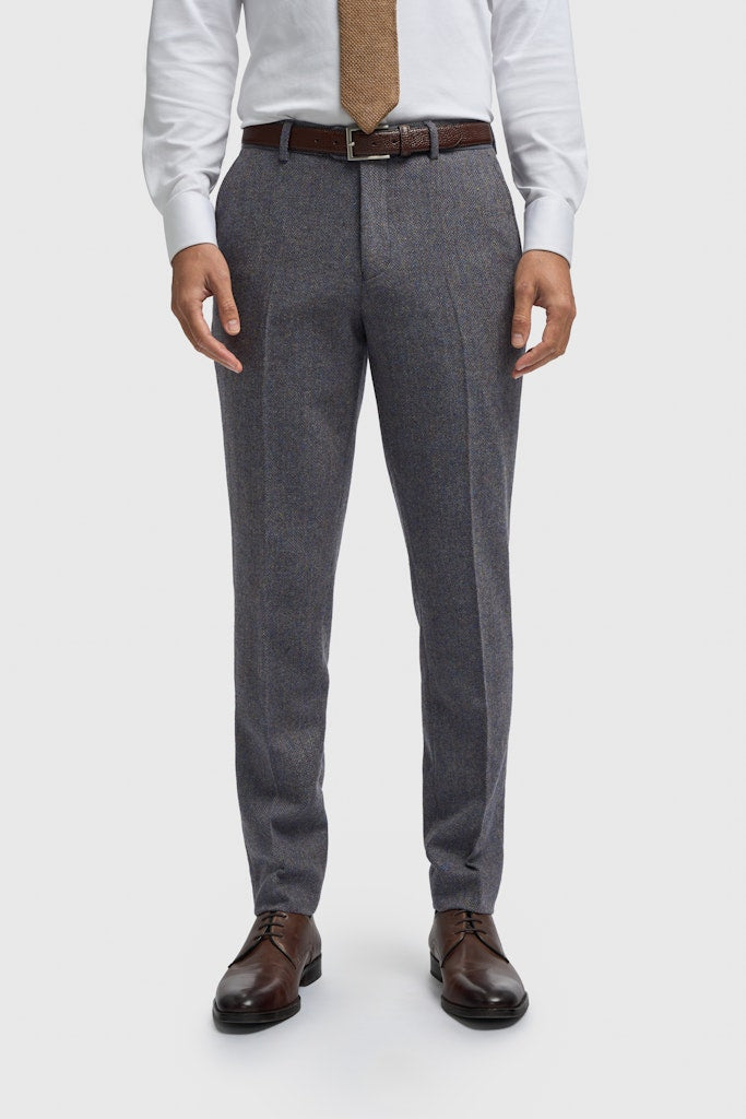 Person wearing gray dress pants with a white shirt, brown tie, and dark shoes on a white background