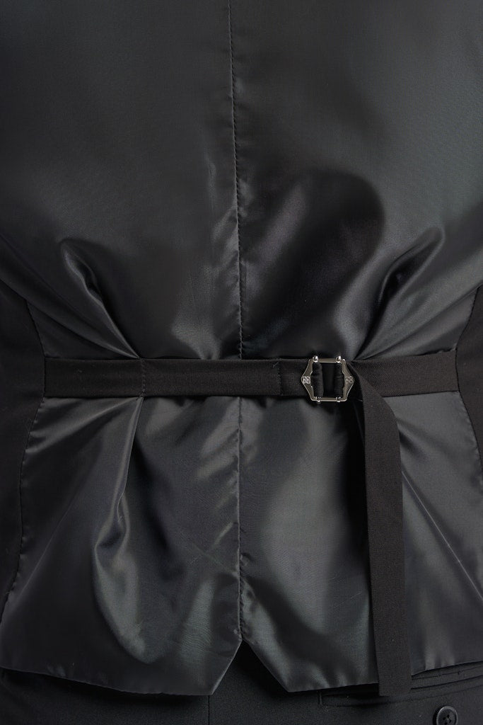 Close-up of a black double breasted waistcoat with a belt and buckle on a dark background