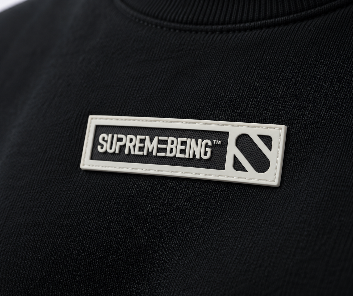 Close-up of the Supreme Being chest badge on the Element black sweatshirt
