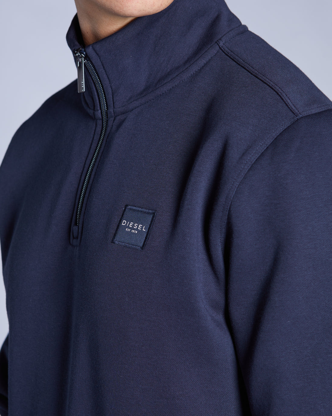 Navy blue pullover with a Diesel logo on a light gray background