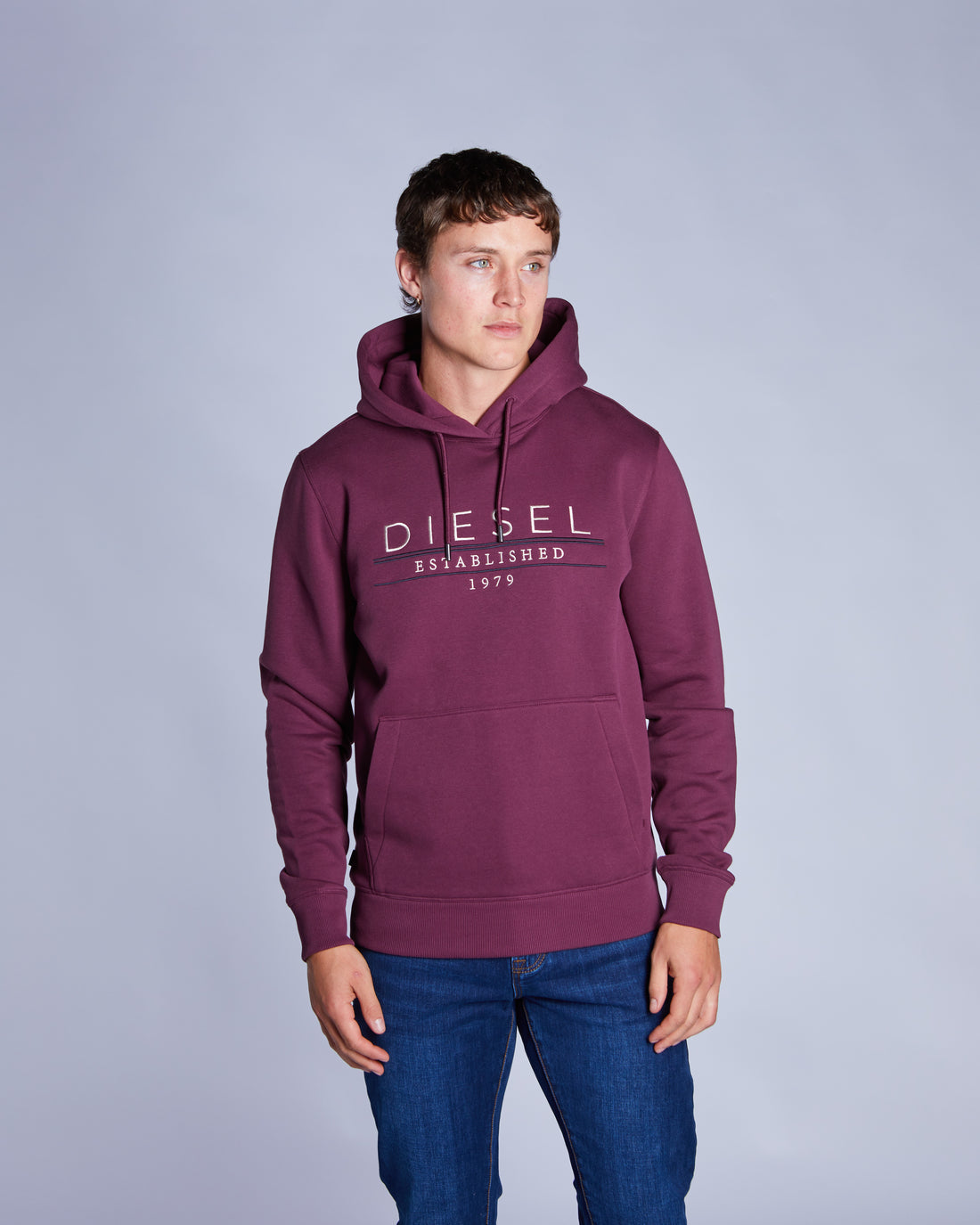 Person wearing a maroon hoodie with 'DIESEL' branding on a gray background
