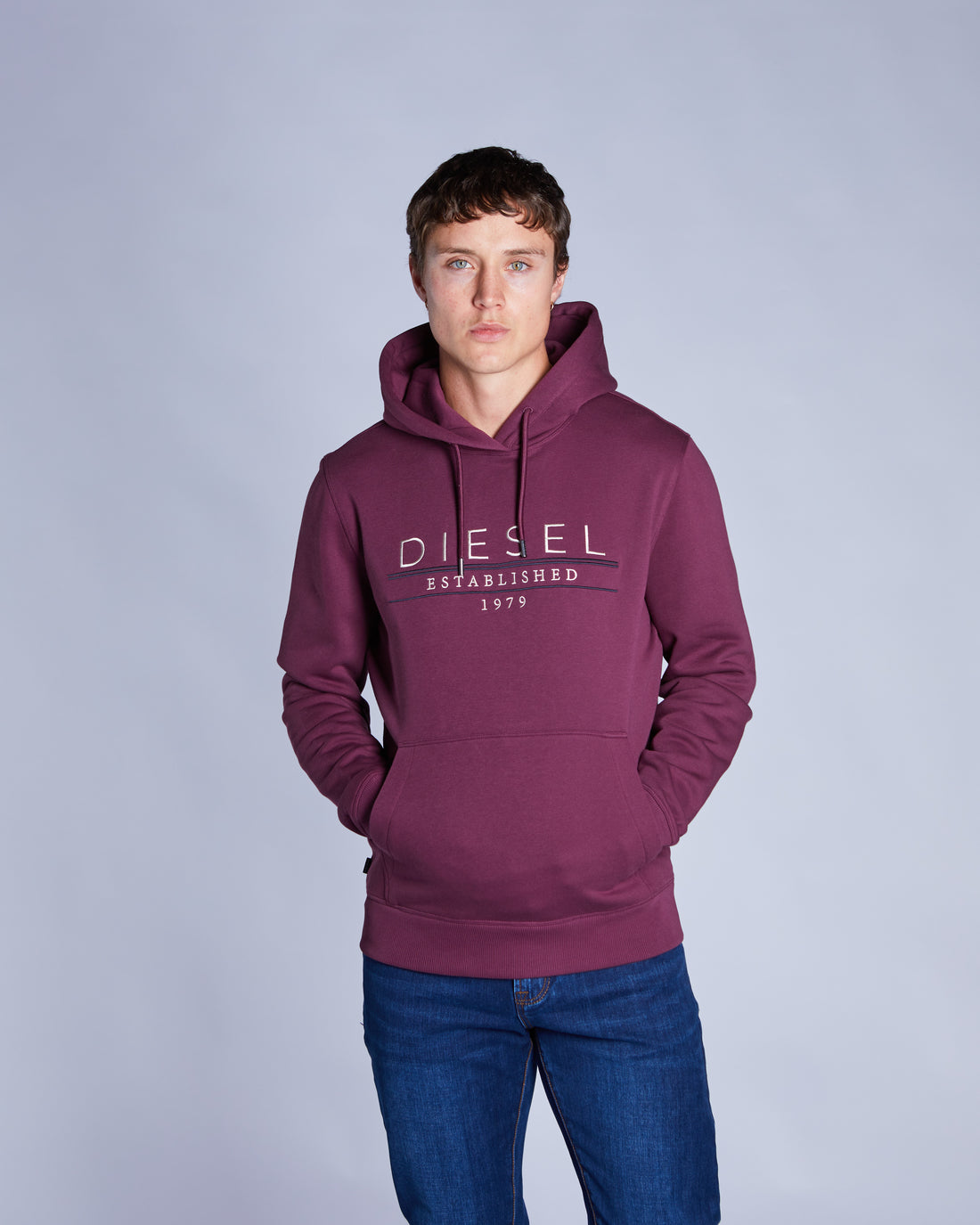 Man wearing a purple Diesel hoodie against a gray background